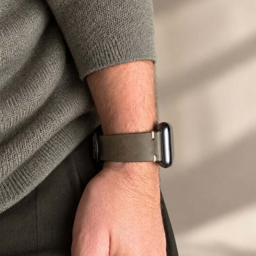 Hunter Apple Watch Armband Leder Olive am Handgelenk eines Mannes, kombiniert mit einem grauen Pullover.