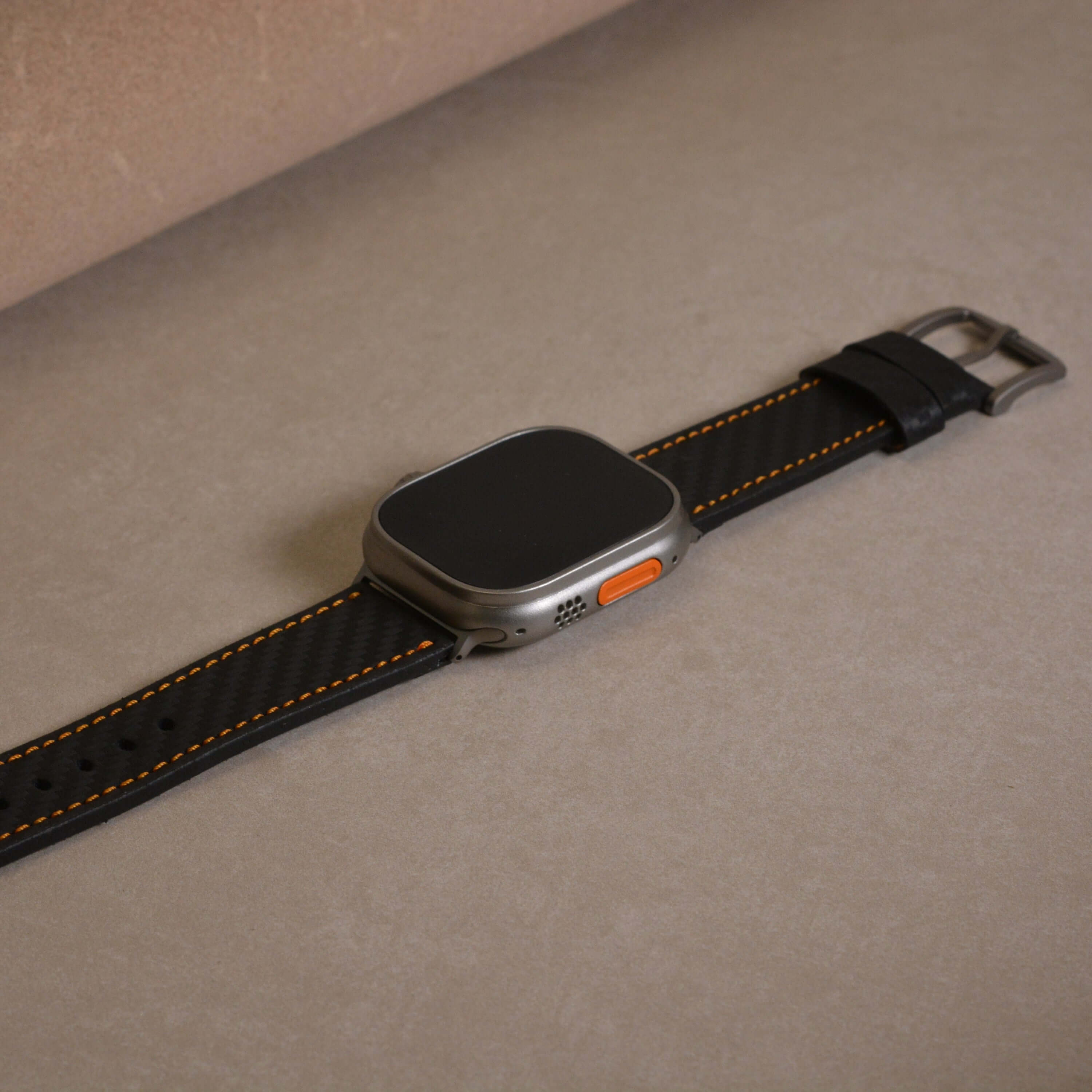 Bergwerk Carbon Orange – Apple Watch Band mit hochwertiger LederCarbon-Struktur auf Tisch, handgefertigt aus echtem Rindleder
