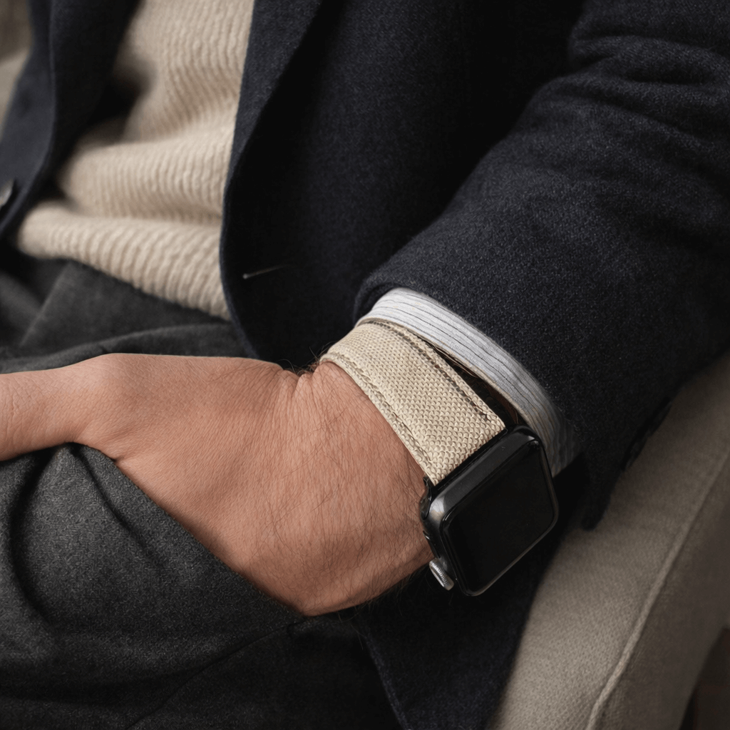Beige Canvas Apple Watch Band Baumwolle an einem Handgelenk, stilvoll mit dunklem Anzug und Pullover kombiniert, robust und wasserabweisend.