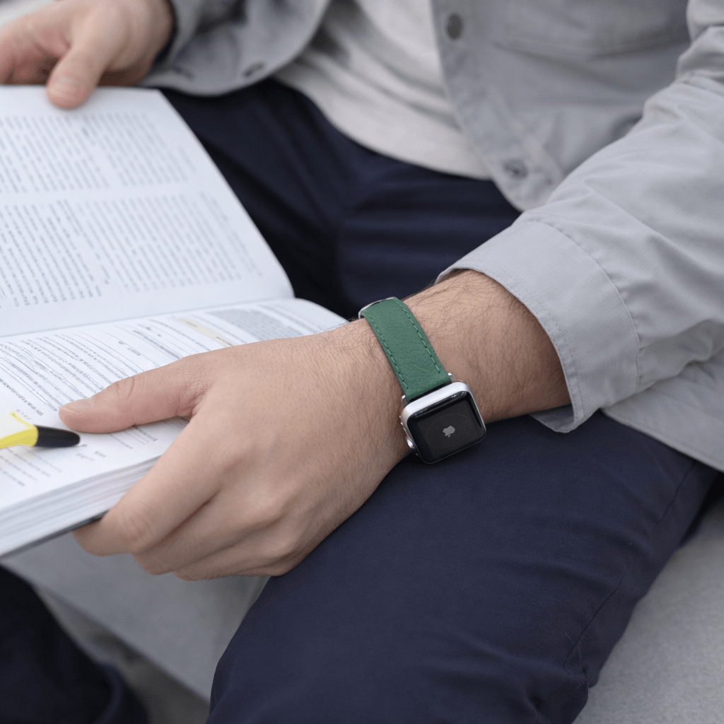 Apple Watch Stierlederarmband Torro Dunkelgrün getragen beim Lesen eines Buches, stilvoll und komfortabel.