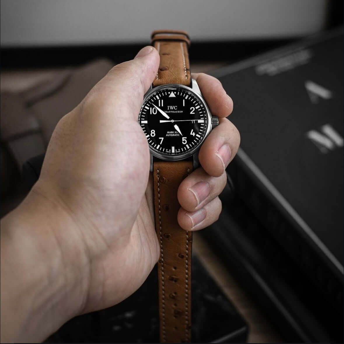 Johannesburg – Uhrenarmband aus feinem Straußenleder an einer schwarzen Uhr, gehalten von einer Hand.