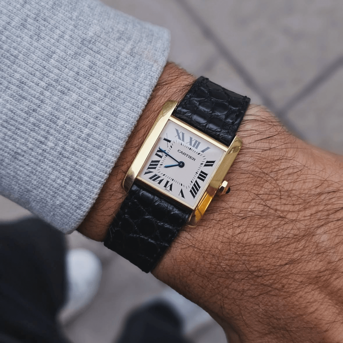 Wrist wearing a Cartier watch with a black New Orleans alligator leather strap by FLUCO, showcasing classic elegance and sustainable luxury.