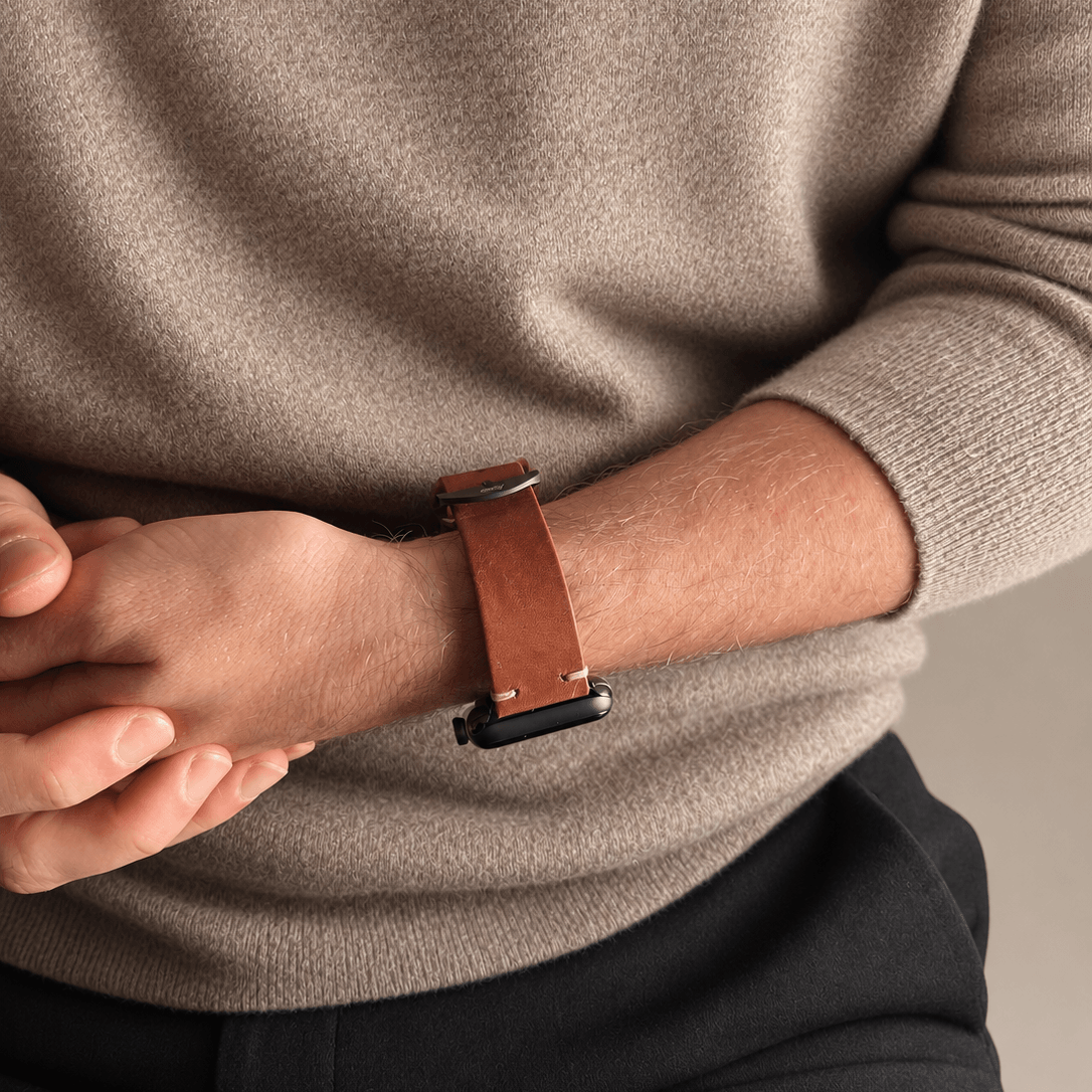 Hunter Apple Watch Armband Leder Hellbraun an einem Handgelenk, kombiniert mit beigem Pullover.
