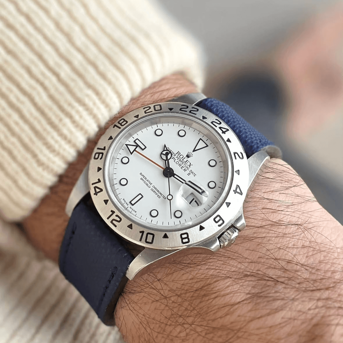 Luxus-Armbanduhr mit blauem wasserfestem Uhrenarmband Nautilus am Handgelenk getragen, Fokus auf Zifferblatt und Lederarmband.