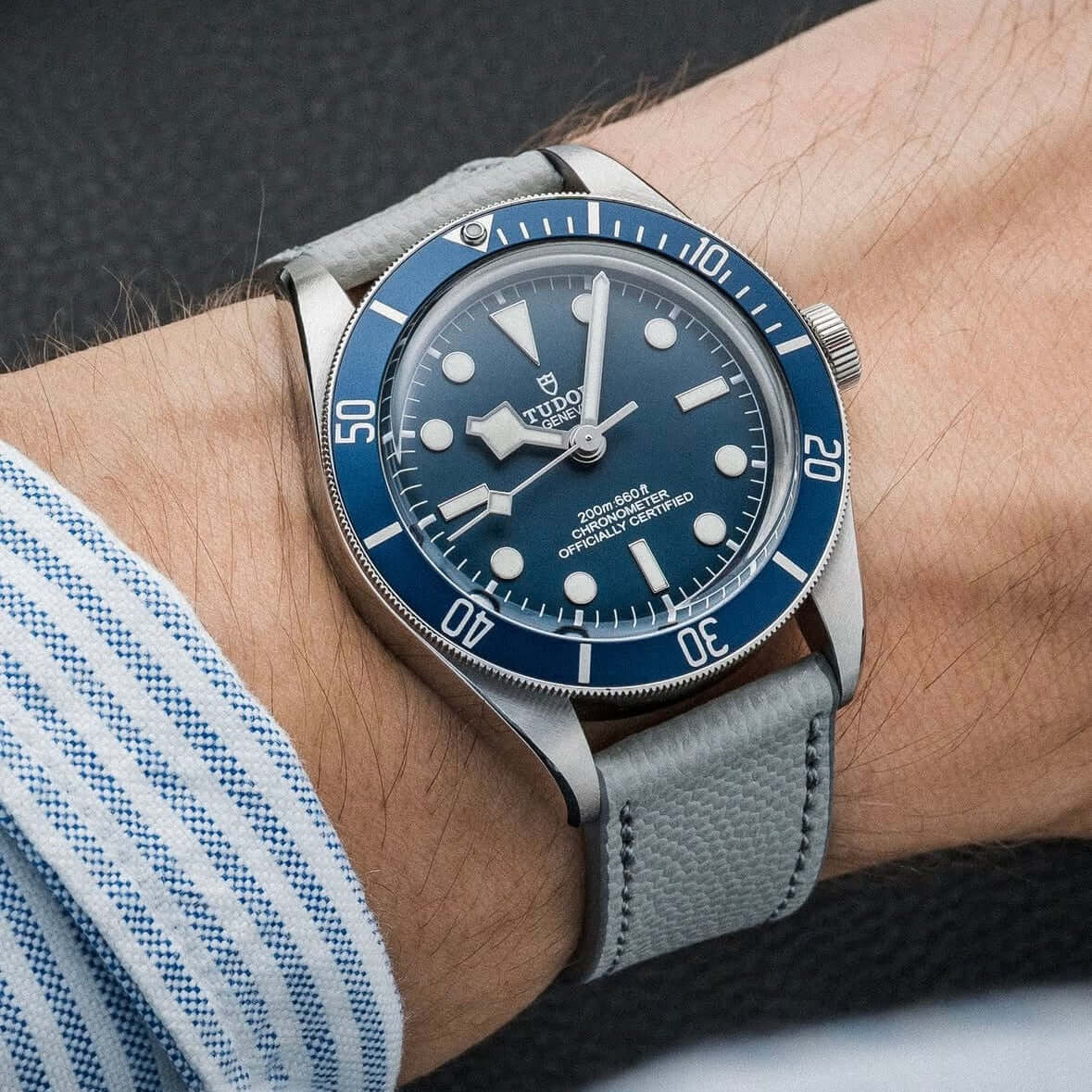 Herrenuhr mit blauem Zifferblatt und hochwertigem Uhrenarmband Kaviarleder in Grau, getragen am Handgelenk, Nahaufnahme.