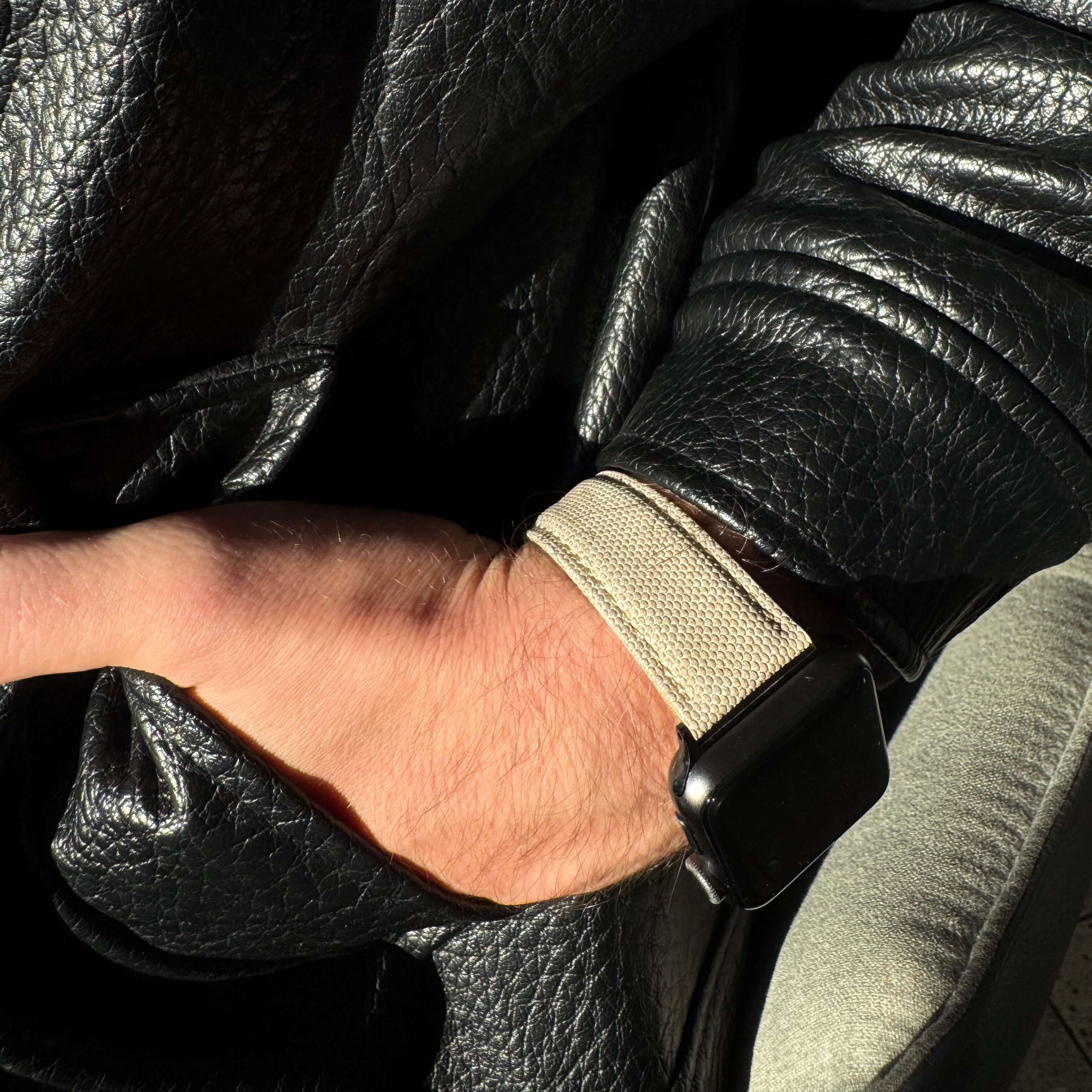 Beiges Apple Watch Band Baumwolle am Handgelenk mit schwarzer Lederjacke, zeitlos und elegant, wasserabweisend und vegan.