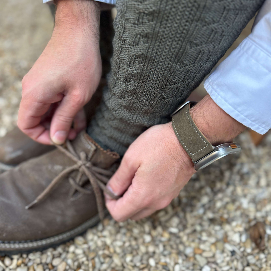 Person trägt Olivebraun Apple Watch Ultra Lederhosen Armband – aus altsämisch gegerbtem Hirschleder, passend für das Oktoberfest.