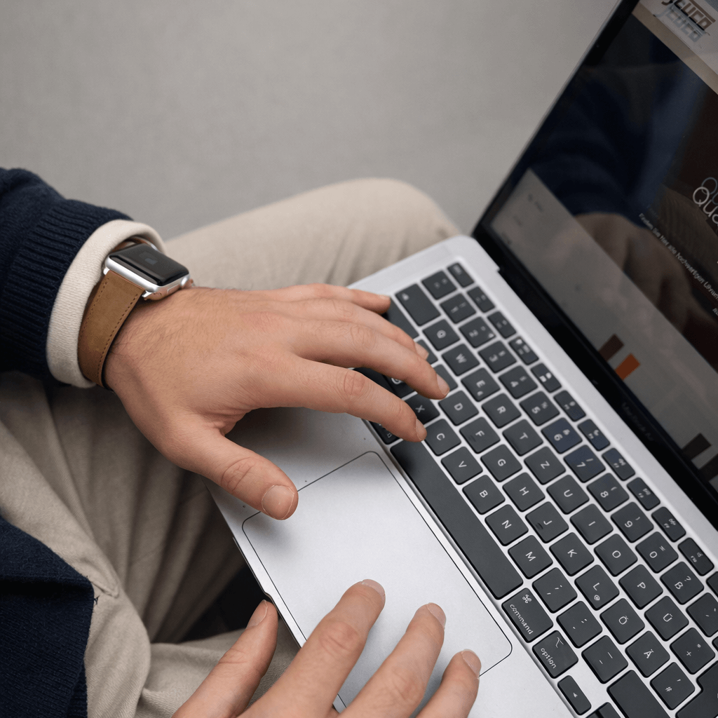 Mountain Apple Watch Lederarmband – Cognac am Handgelenk eines Mannes beim Tippen auf einem Laptop