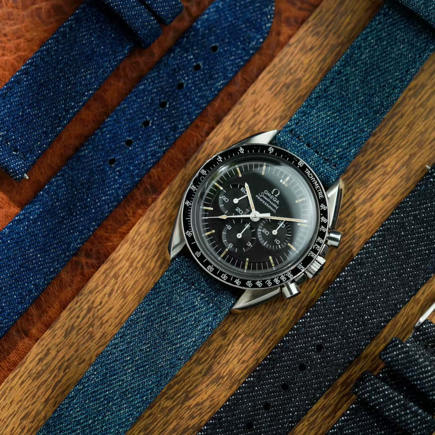 Luxuriöse Jeans Uhrenarmband aus japanischem Denim, kombiniert mit schwarzem Zifferblatt, auf Holzhintergrund präsentiert.