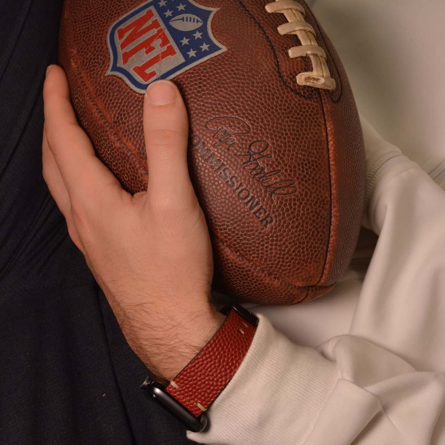 Wilson – Handgefertigt aus original Horween Footballleder Apple Watch Band in Hand mit NFL-Football.