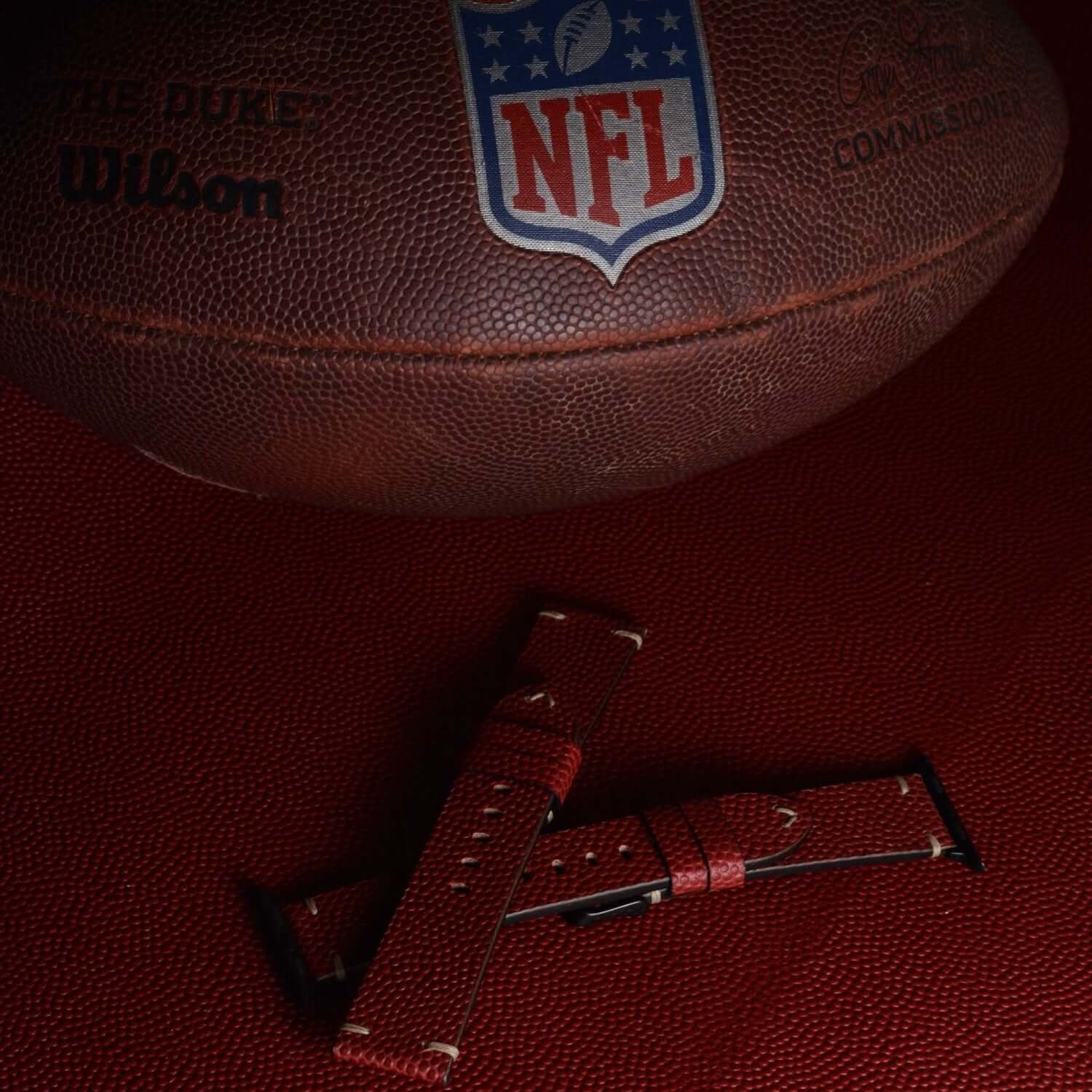 Apple Watch Band aus Wilson – Handgefertigt aus original Horween Footballleder vor einem NFL-Ball in Nahaufnahme.