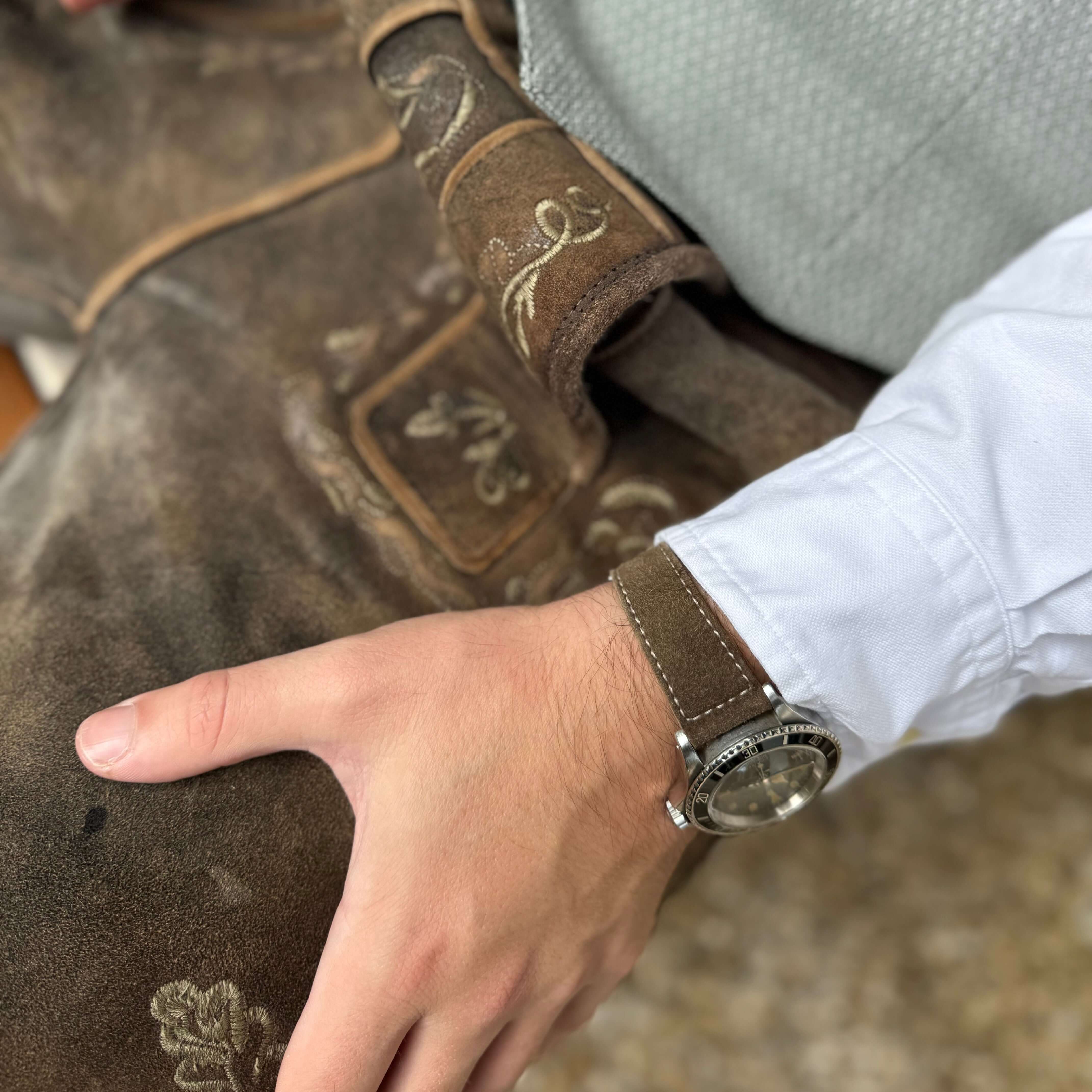 Person trägt 20mm Uhrenarmband aus echtem Lederhosenleder – altsämisch gegerbtes Hirschleder mit traditioneller Tracht