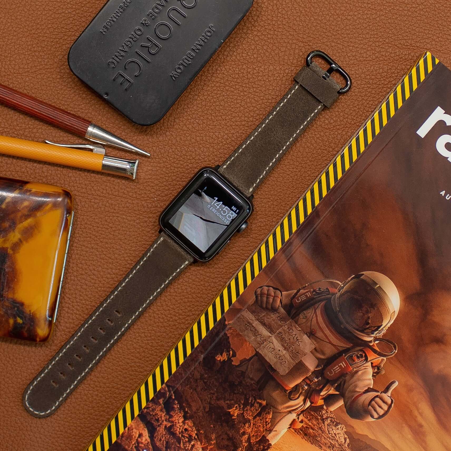 Apple Watch Lederarmband Vintage – Dunkelbraun auf braunem Hintergrund mit Stiften und Magazin