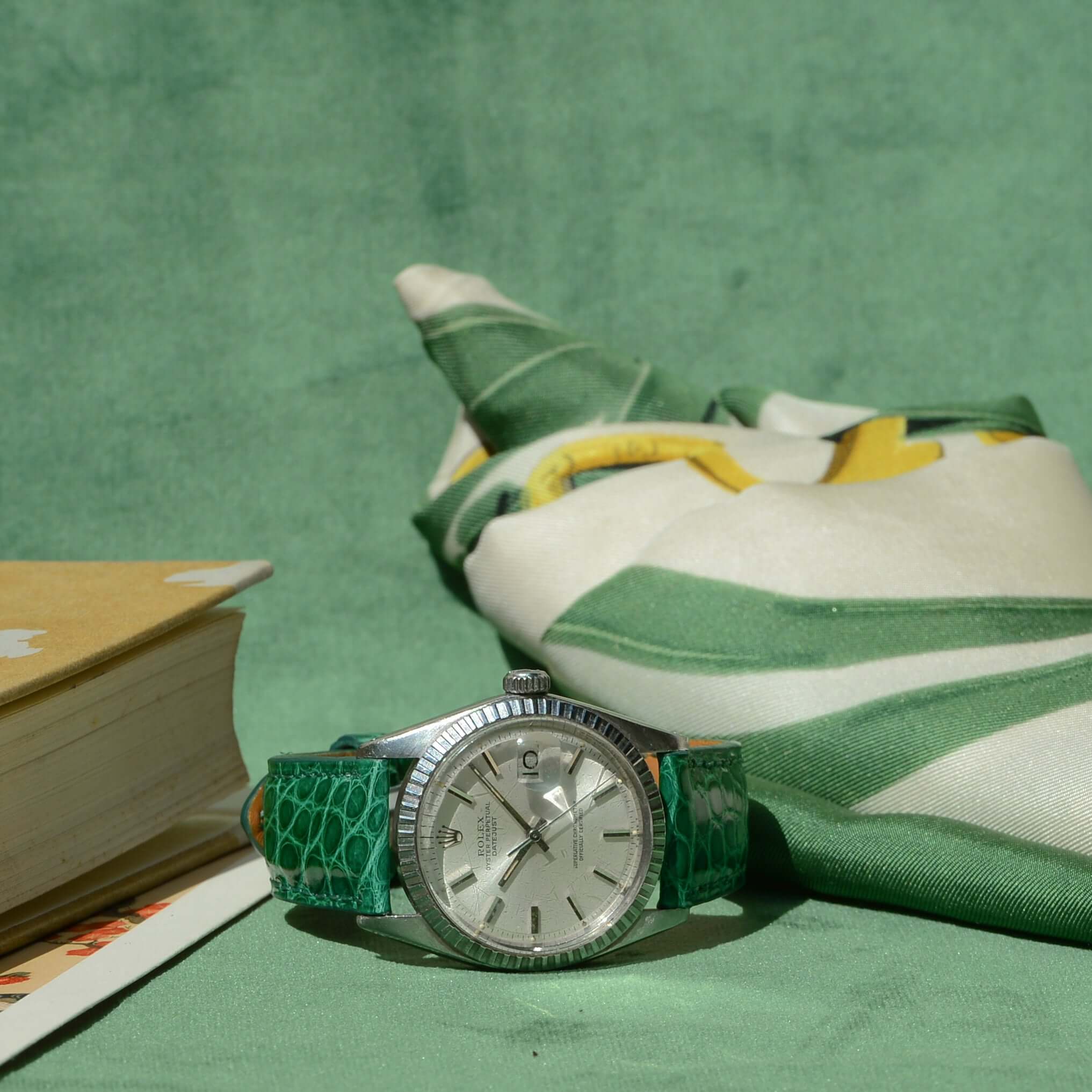 Luxusuhr mit Glänzendes Kroko Armband aus hochwertigem Krokodilleder auf grünem Hintergrund.