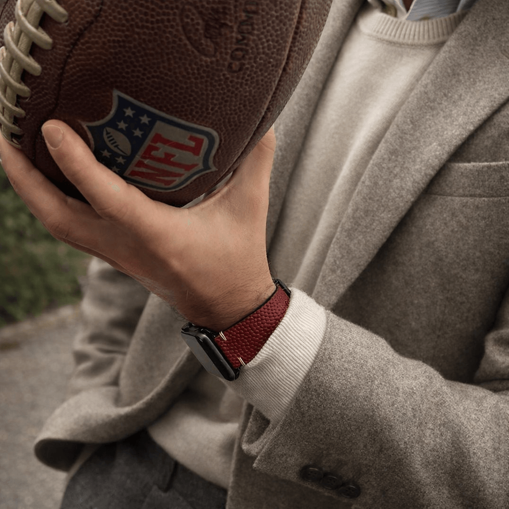 Mann hält Football, trägt Touchdown – Handgefertigt aus original Horween Footballleder Armband