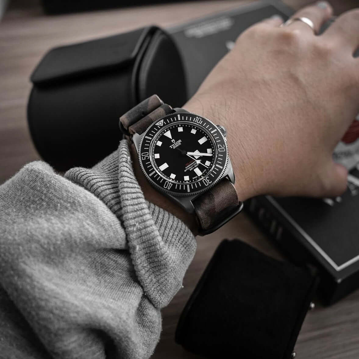 Military – Field Uhrenarmband im Camouflage Look an einem Handgelenk mit schwarzer Uhr.