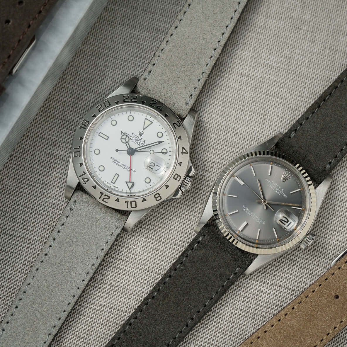 Zwei hochwertige Uhren mit Nizza – Uhrenarmband aus feinem Wildleder in Grau und Dunkelgrau auf grauem Hintergrund