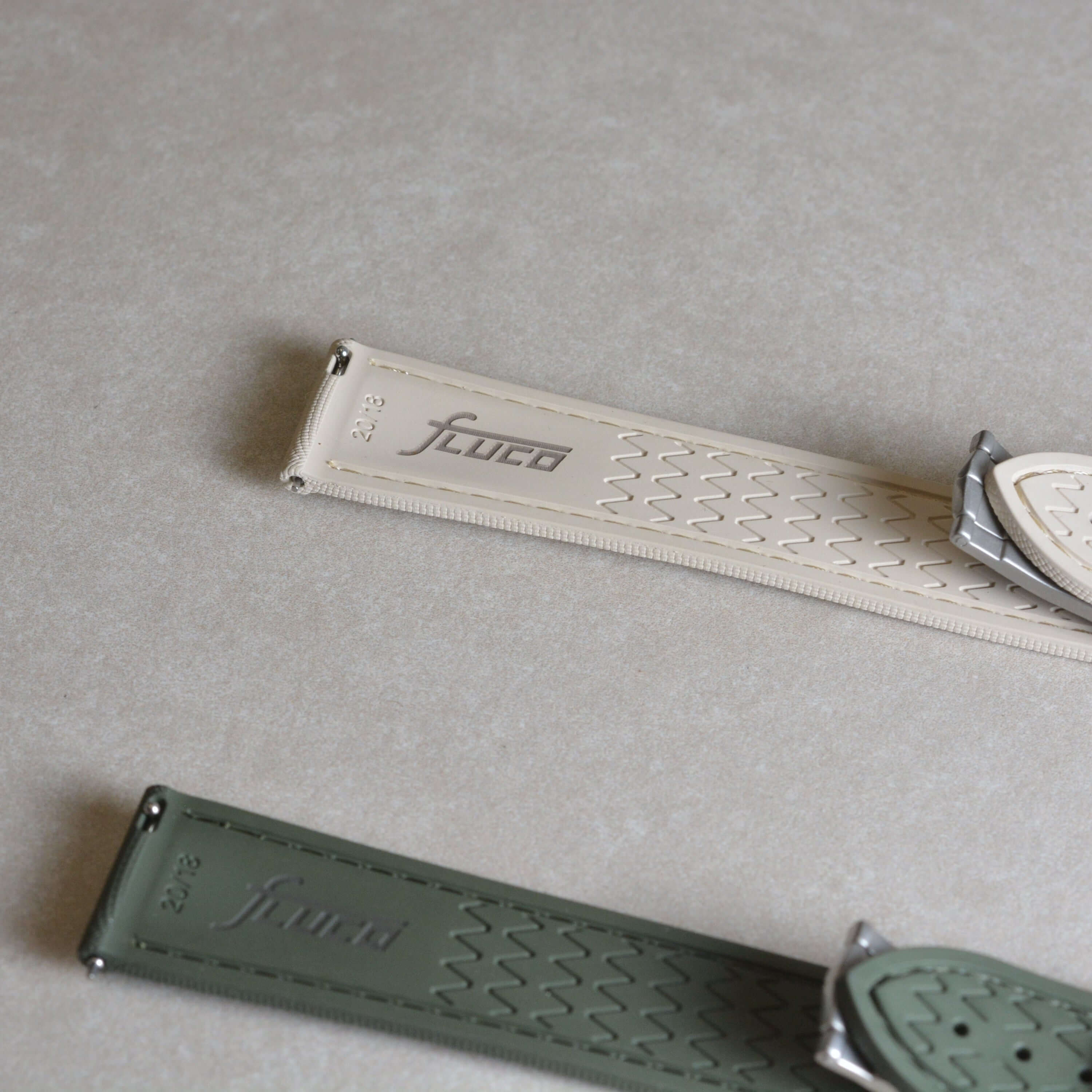 Monaco – Faltschließen Uhrenarmband aus FKM Kautschuk in beige und grün auf gleicher Unterlage.