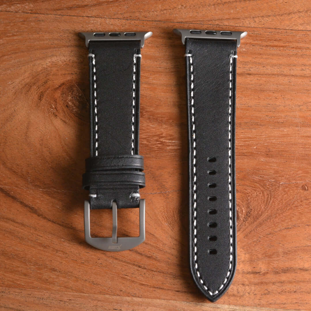 Apple Watch Ultra Lederarmband – Schwarz, extra breit 24 mm aus BIO-Leder aus der Toskana auf Holzuntergrund.