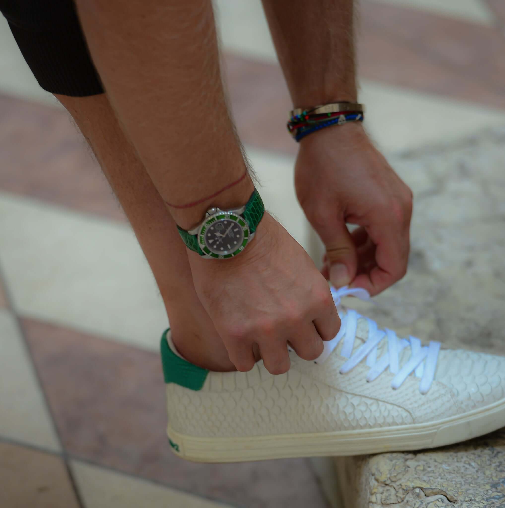 Luxusuhr mit Glänzendes Kroko Armband, grün, elegant und nachhaltig, am Handgelenk, kombiniert mit einem lässigen Sneaker-Stil.