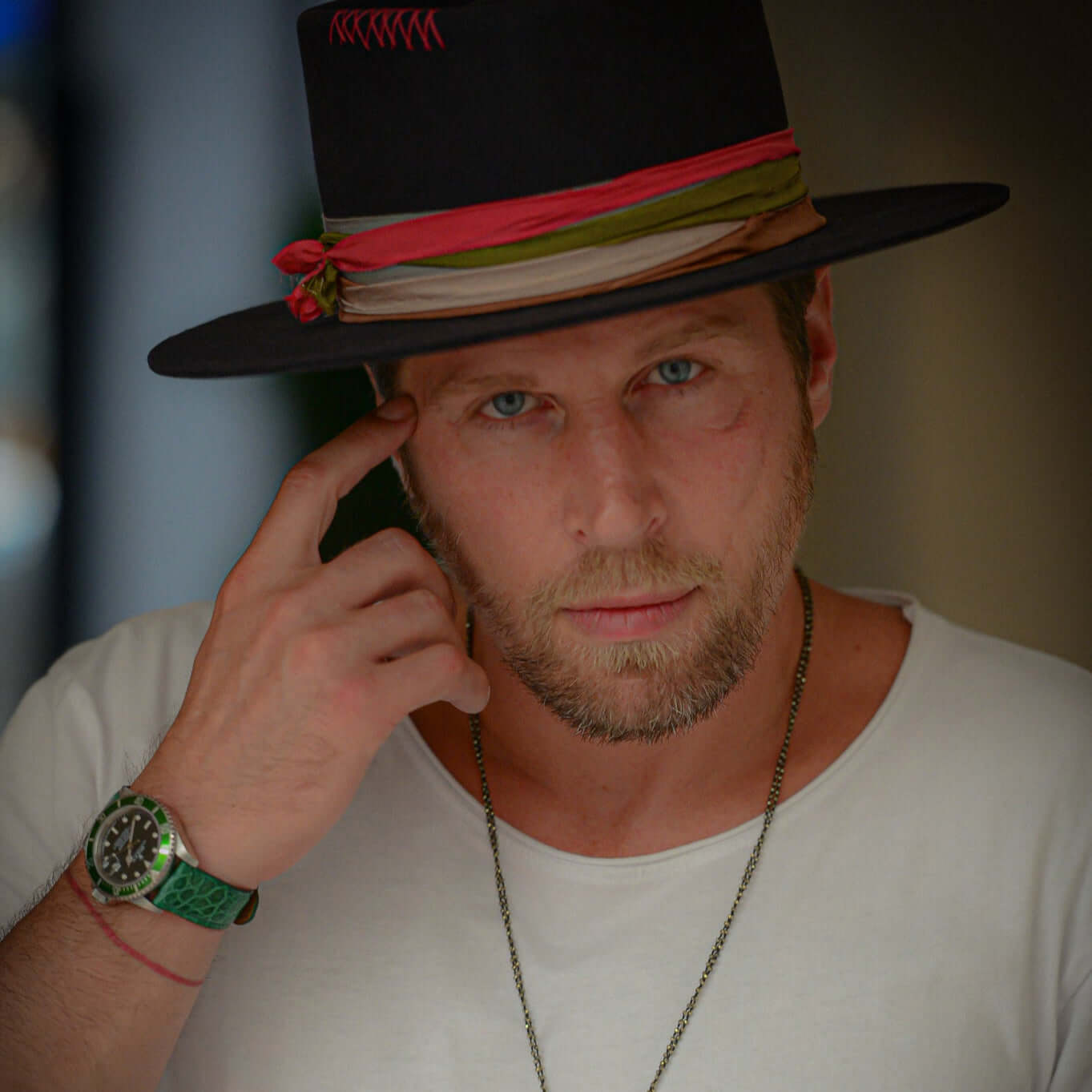 Eleganter Mann mit weißem T-Shirt und stilvollem Hut, trägt eine Luxusuhr mit Glänzendes Kroko Armband in grünem Krokodilleder.