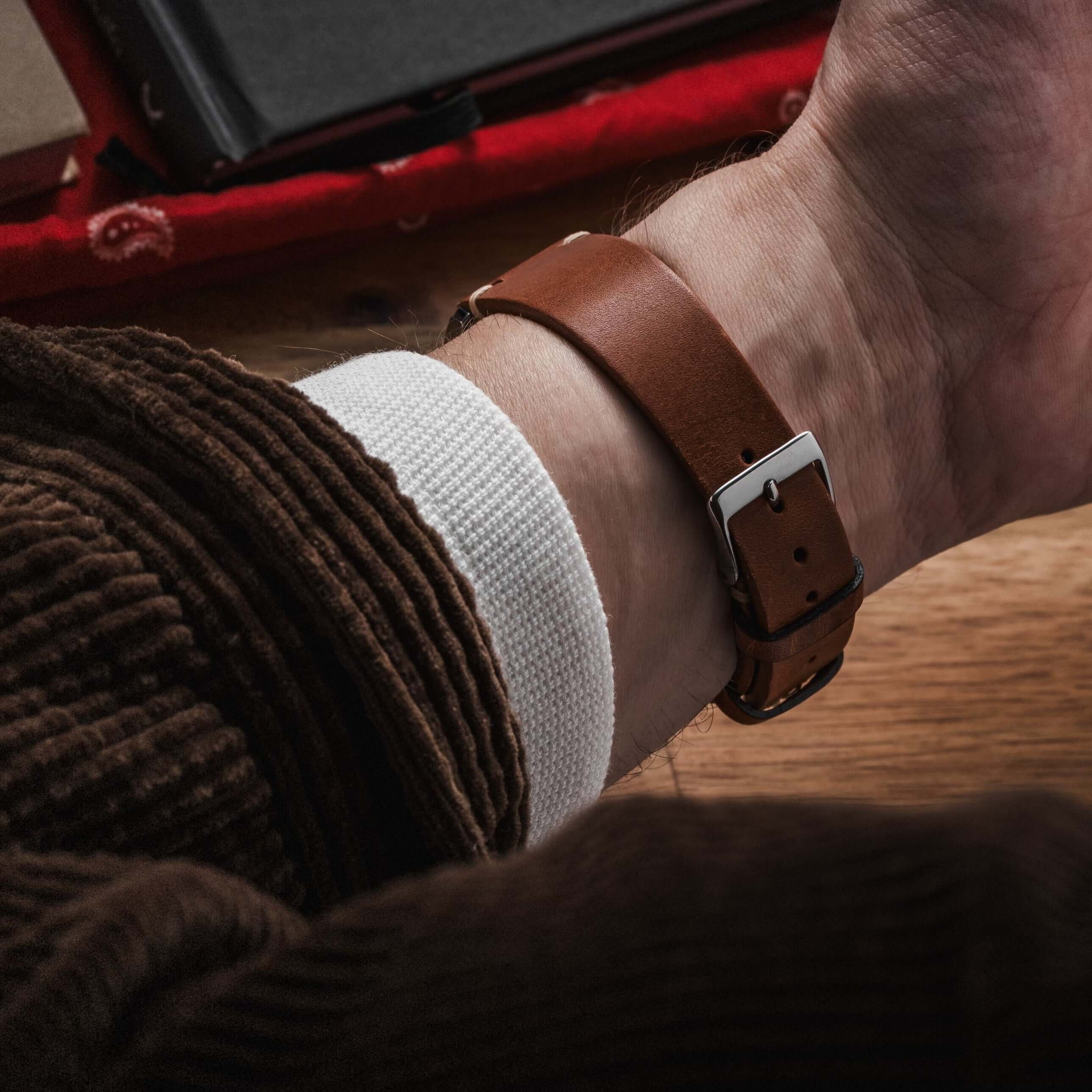 Hunter – Uhrenarmband aus toskanischem Vintage-Rindleder an einem Handgelenk auf braunem Tisch.