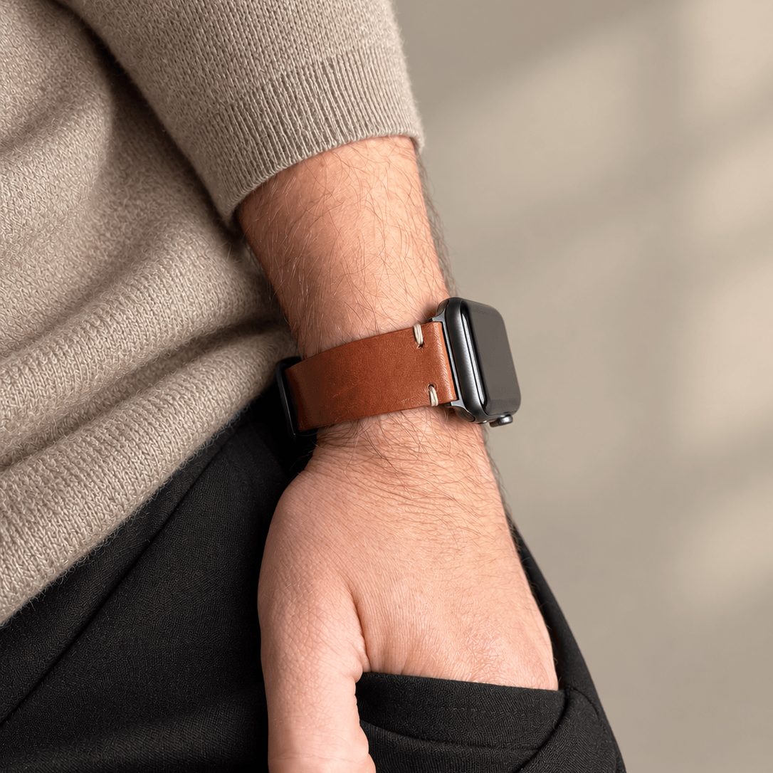 Hunter Apple Watch Armband Leder Hellbraun am Handgelenk eines Trägers mit schwarzer Uhr.