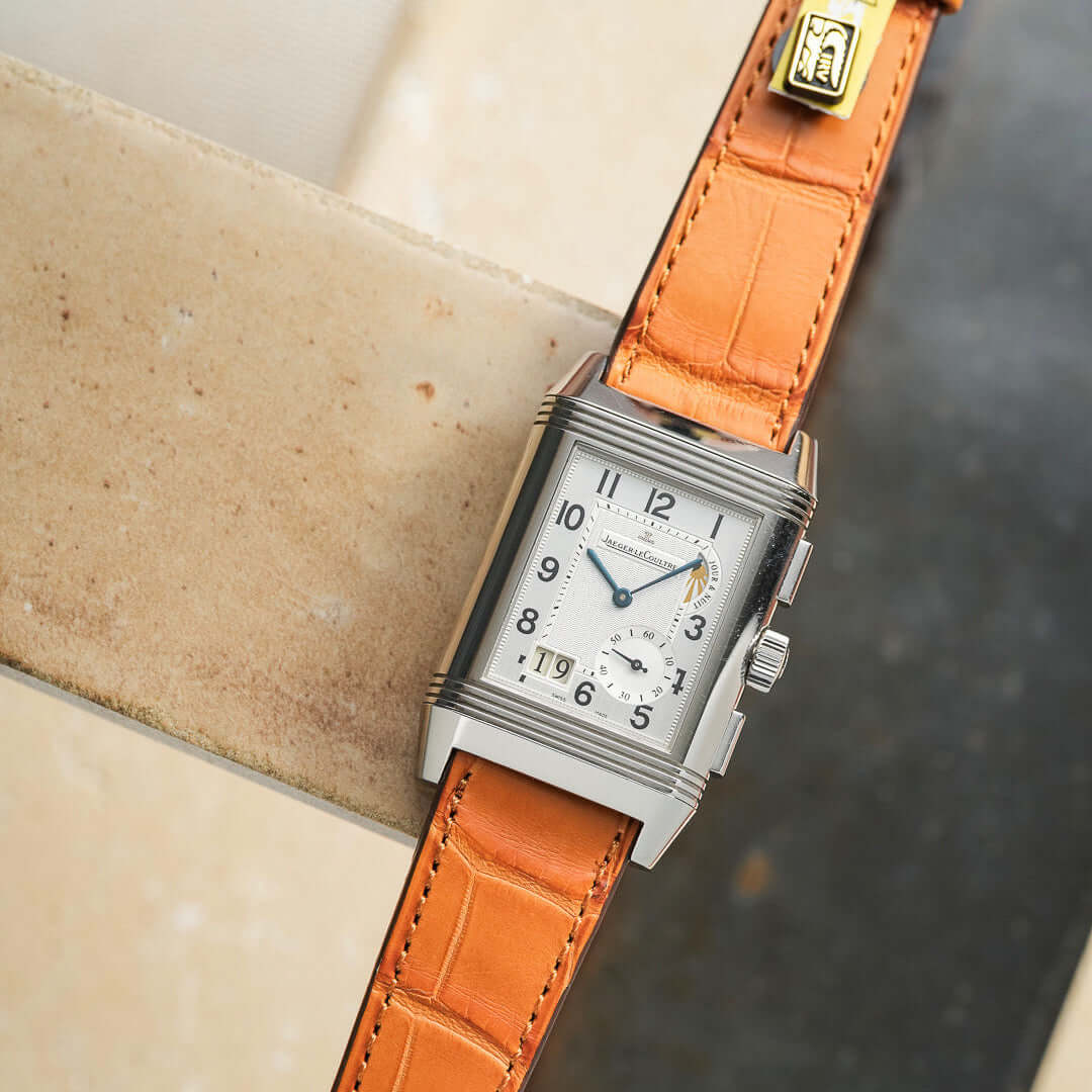 Full Cut – Armband aus vollflächigem Louisiana-Alligatorleder in Cognac mit eleganter Uhr auf Marmorhintergrund.