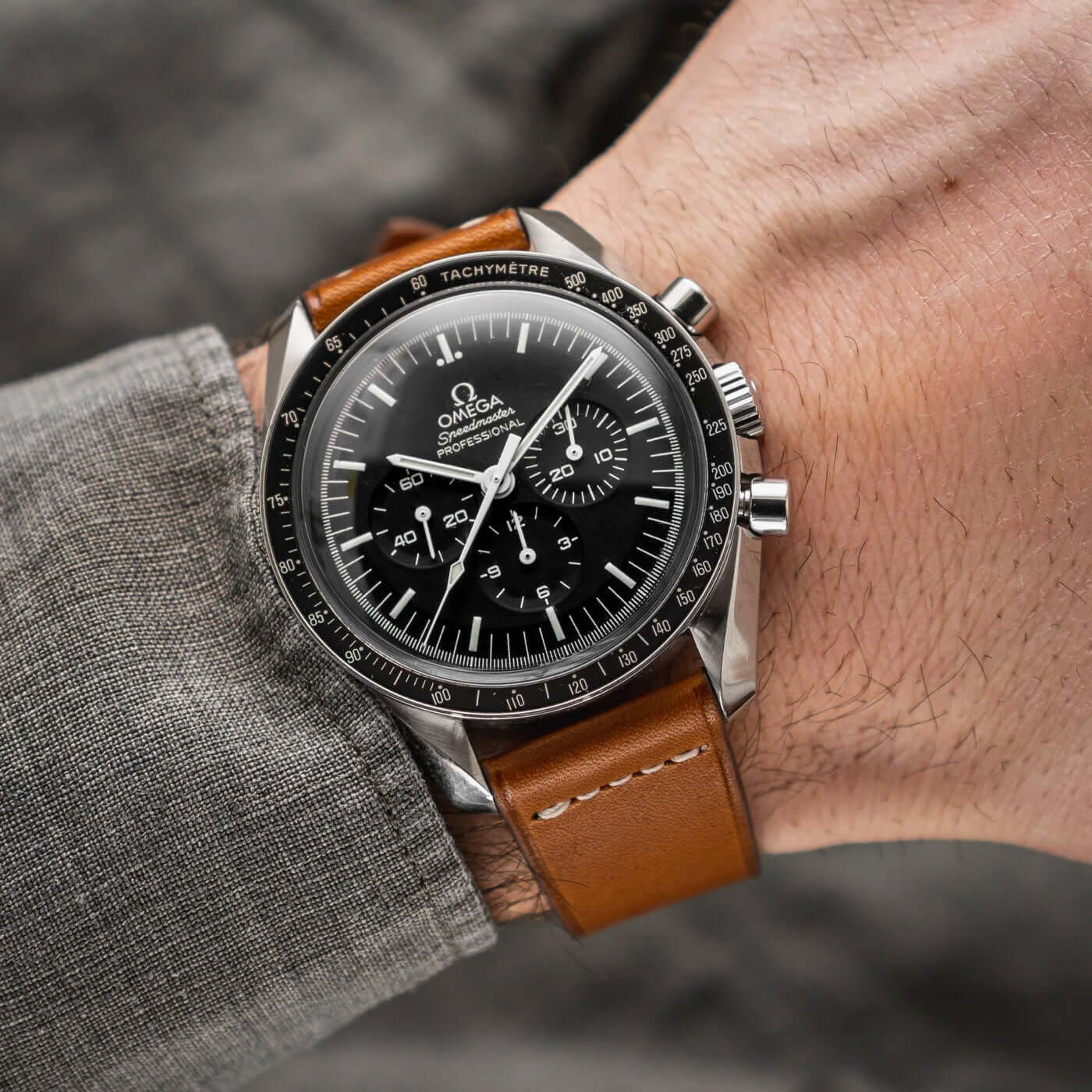 Mann mit Armbanduhr und Paris – Uhrenarmband aus Barenia-Leder von Haas in Braun auf dem Handgelenk.