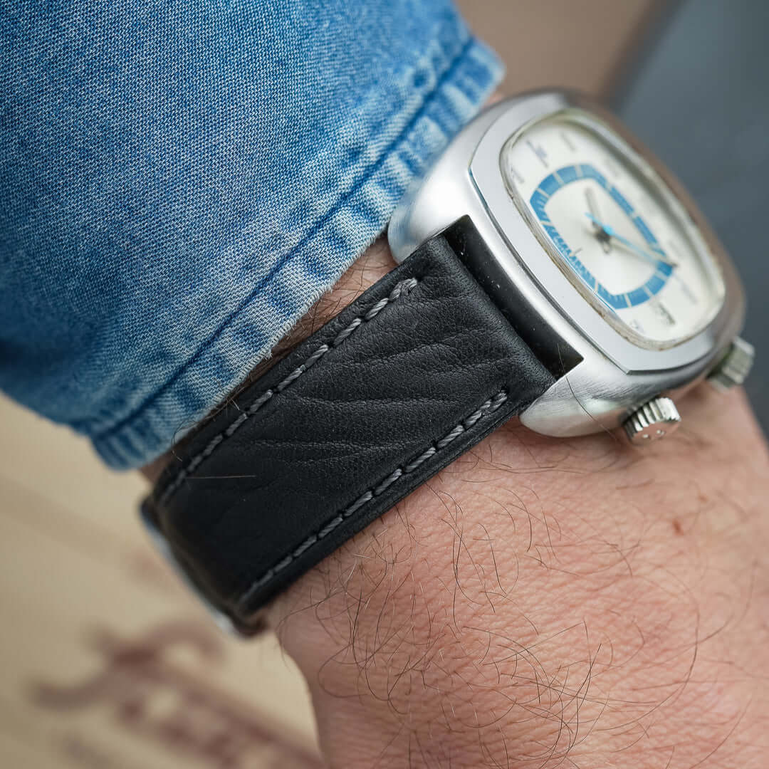 Close-up of a watch with a black leather strap, showcasing the durable Torro Stierleder Uhrenarmband on a wrist.