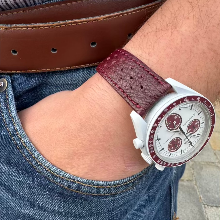Uhrenarmband aus echtem Leder in Bordeaux von FLUCO – Handgefertigt in Deutschland mit Kontrastnaht. Am Handgelenk einer Omega Swatch frontal.