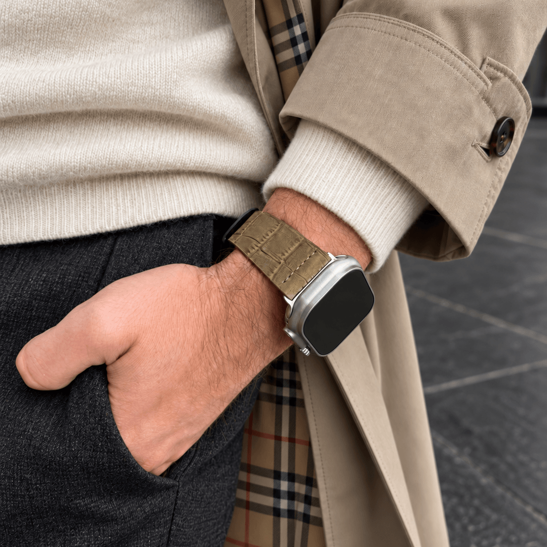 Dakkar Sand – 24 mm Apple Watch Ultra Lederarmband in Kroko-Optik am Handgelenk eines Mannes in elegante Kleidung.