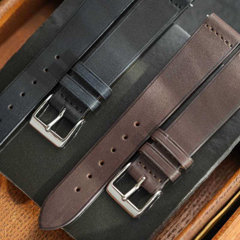 Dunkelbraunes Barenia Glattleder Uhrenarmband neben schwarzem Uhrenarmband – Detailaufnahme von zwei hochwertigen Lederarmbändern, einem dunkelbraunen Barenia Glattleder und einem schwarzen Uhrenarmband, ideal für elegante Zeitmesser