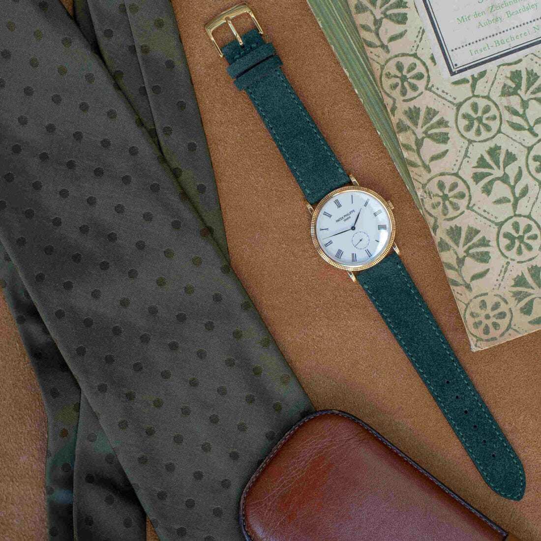 Dunkelgrünes Nizza Velourslederarmband von oben an einer goldenen Patek Philippe Genève fotografiert, das die elegante Kombination von hochwertigem Veloursleder und klassischer Uhr präsentiert.