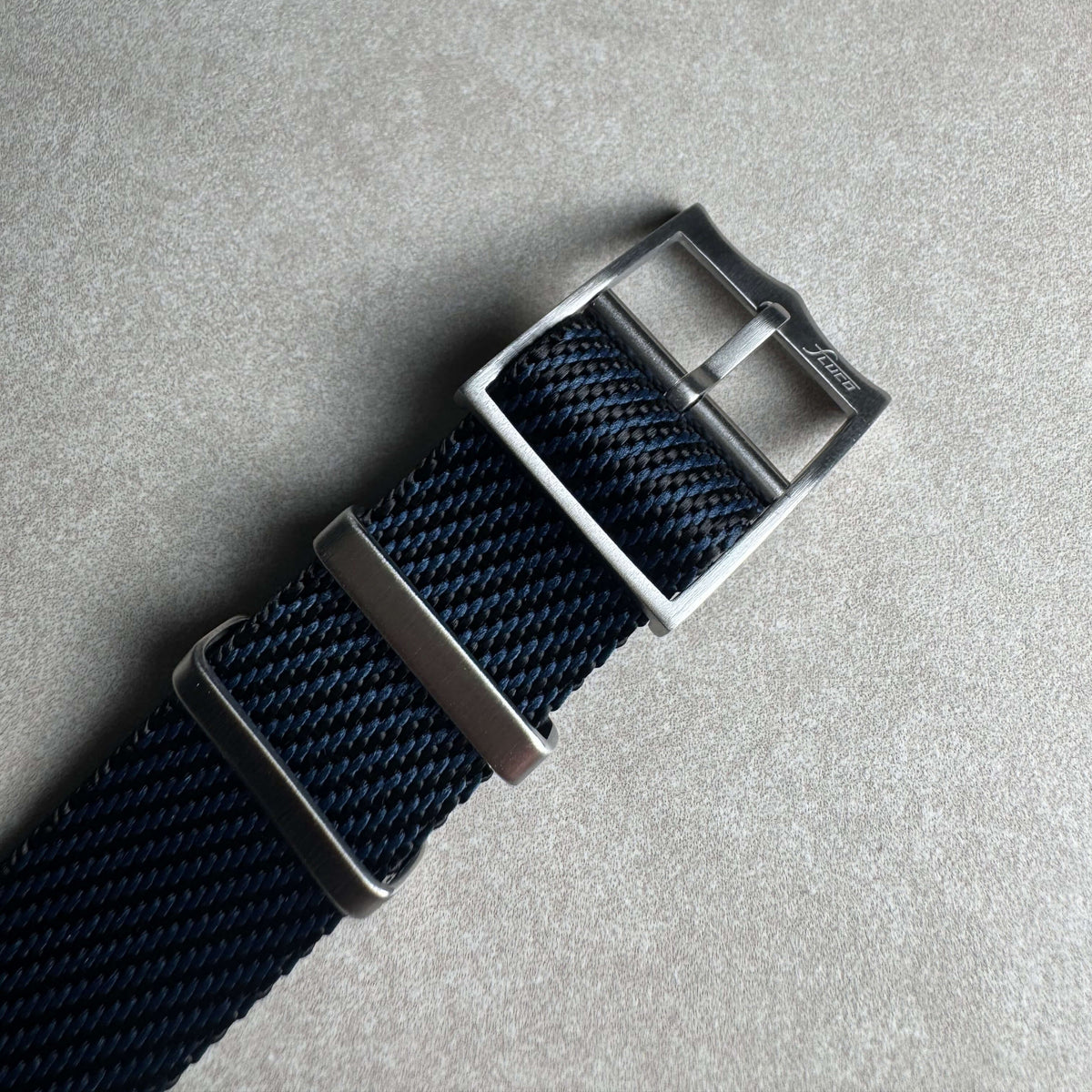 Durchzugsband Cotton – Uhrenarmband aus Nylon-Gewebe mit Edelstahl-Schnalle auf grauem Hintergrund.