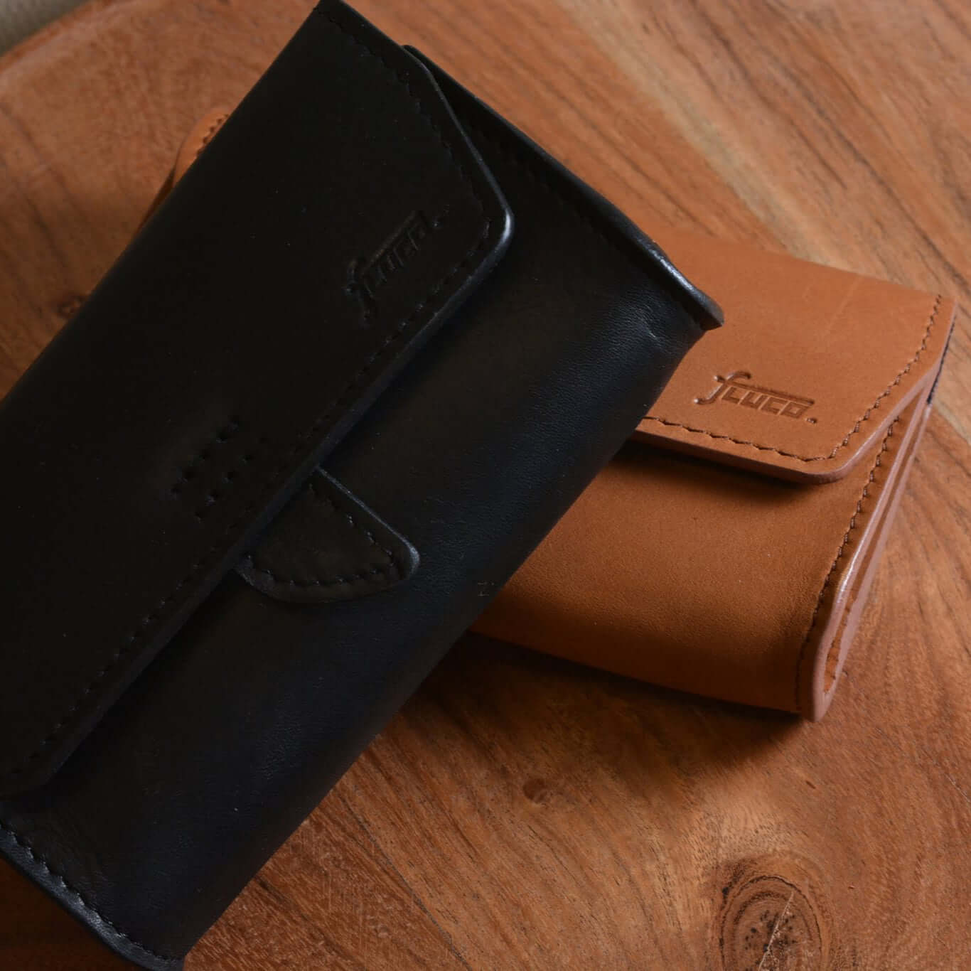 FLUCO x The Urban Gentry pocket watch case in black and brown leather on a wooden surface.