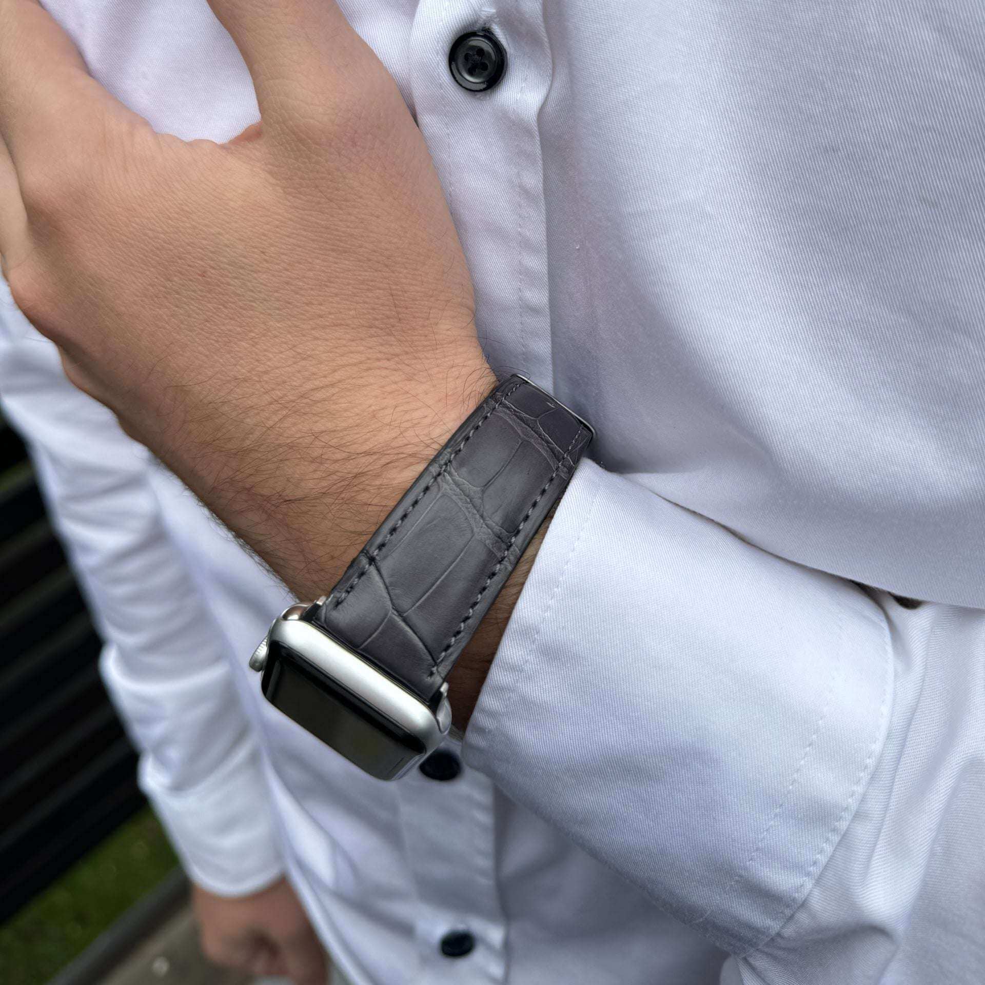 Graues Echt-Alligator-Armband für Apple Watch am Handgelenk – Elegantes Design auf beiger Hose mit weißem Hemd im Hintergrund