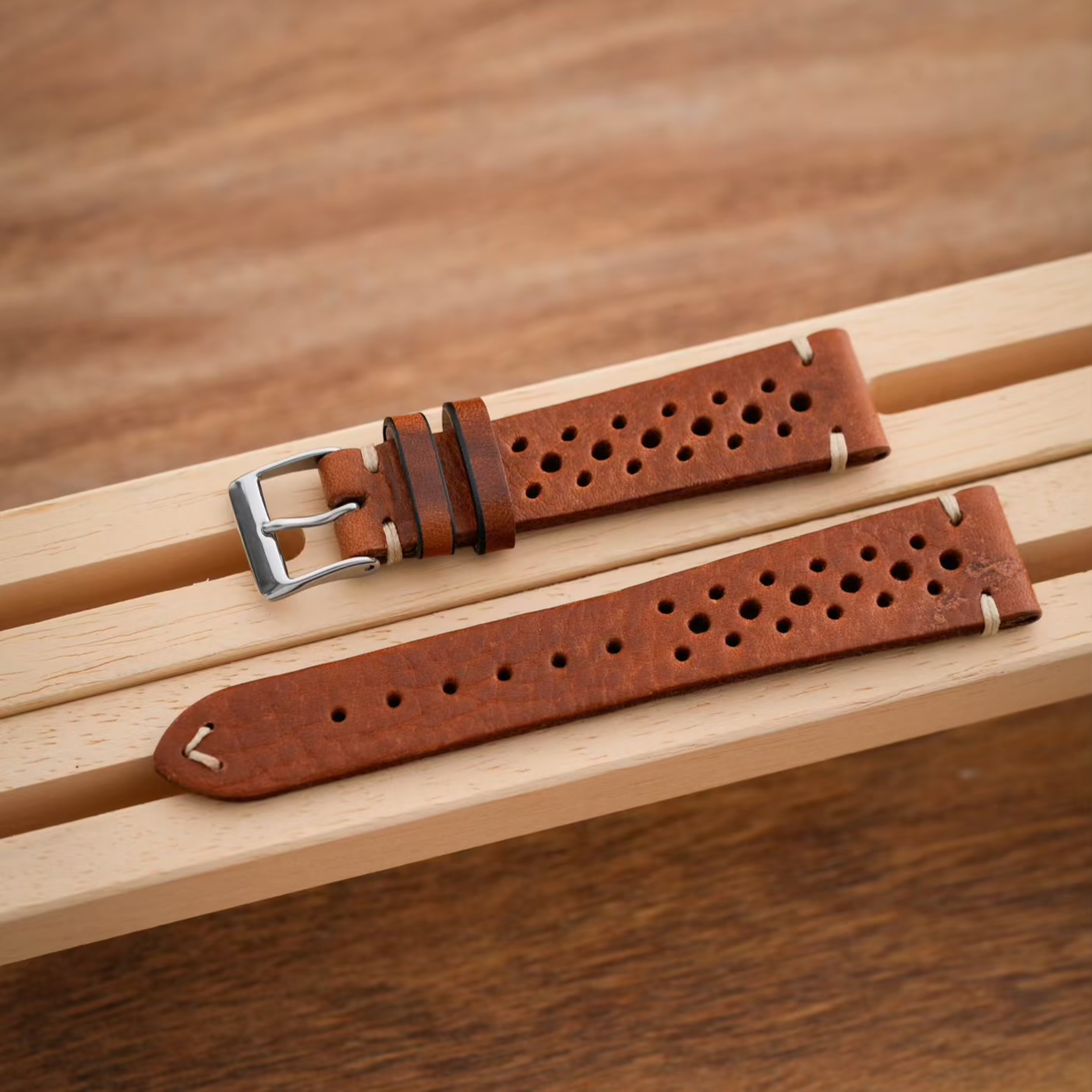 Uhrenarmband Racing in braunem Leder mit dekorativen Löchern, gut sichtbar auf einem Holzgestell.