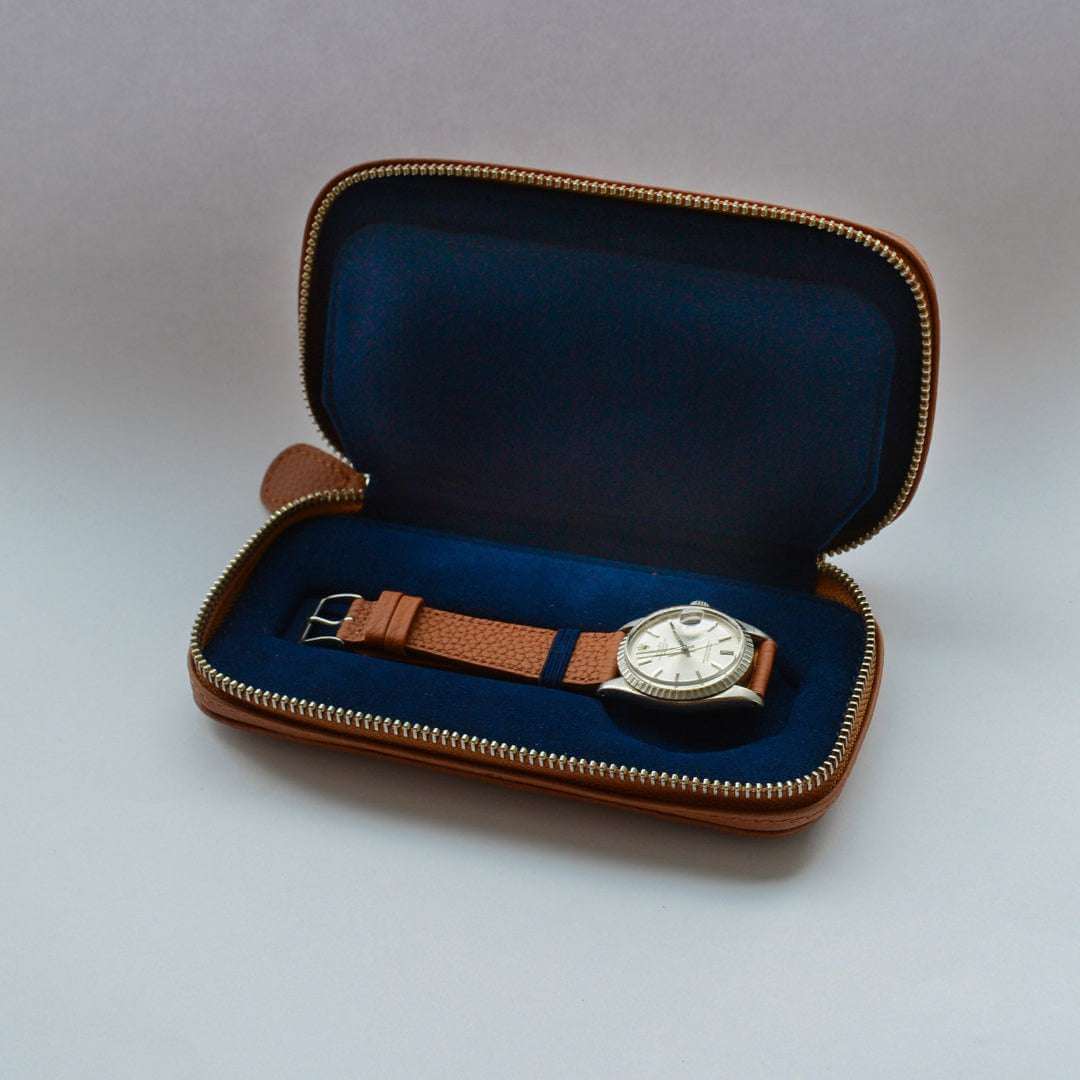 Innenansicht eines Uhrenetuis für zwei Uhren aus whiskyfarbenem Cognac-Leder mit blauem Alcantara-Innenfutter. Hochwertige Verarbeitung und luxuriöses Design für die stilvolle und sichere Aufbewahrung von Armbanduhren.
