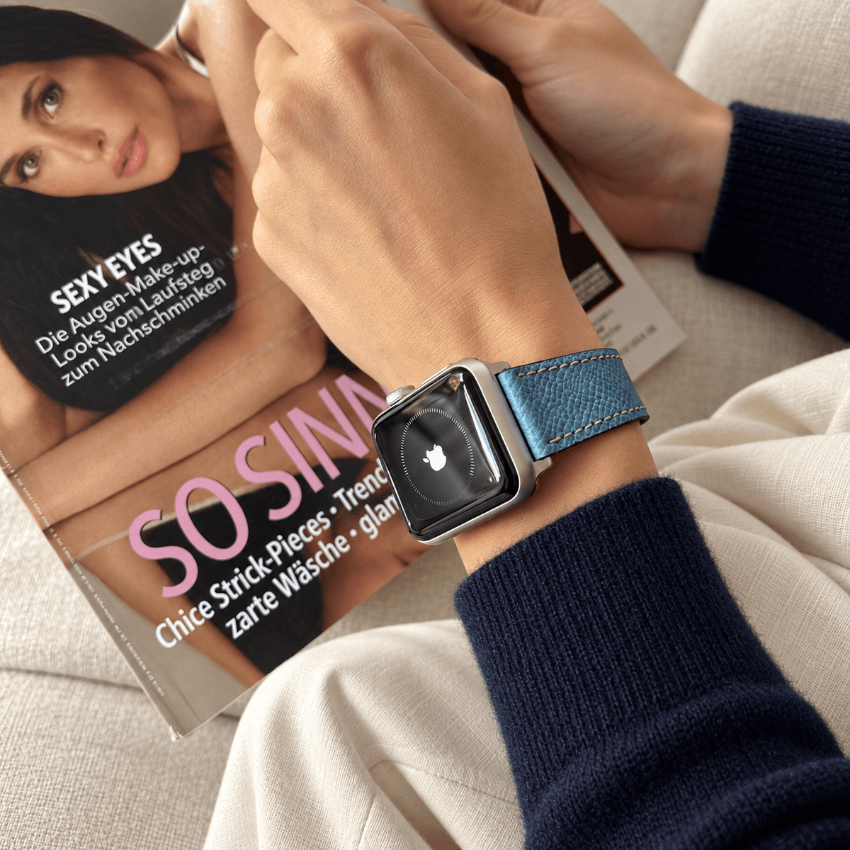 Luxuriöses Apple Watch Lederarmband Damen Cupertino Hellblau an Hand mit Zeitschrift im Hintergrund, hochwertig und made in Germany.