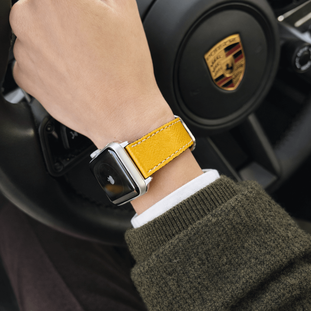 Luxuriöses Apple Watch Lederarmband Damen Cupertino Gelb am Handgelenk in einem Auto.