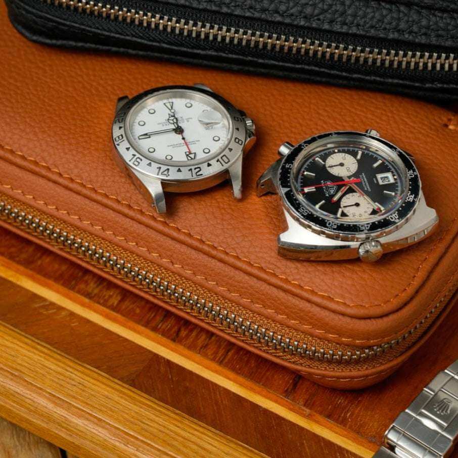 Rolex Explorer 2 mit weißem Zifferblatt und Tag Heuer Autavia, präsentiert auf einem Watch Case aus whiskyfarbenem Togo-Leder, stilvolle Präsentation hochwertiger Uhren