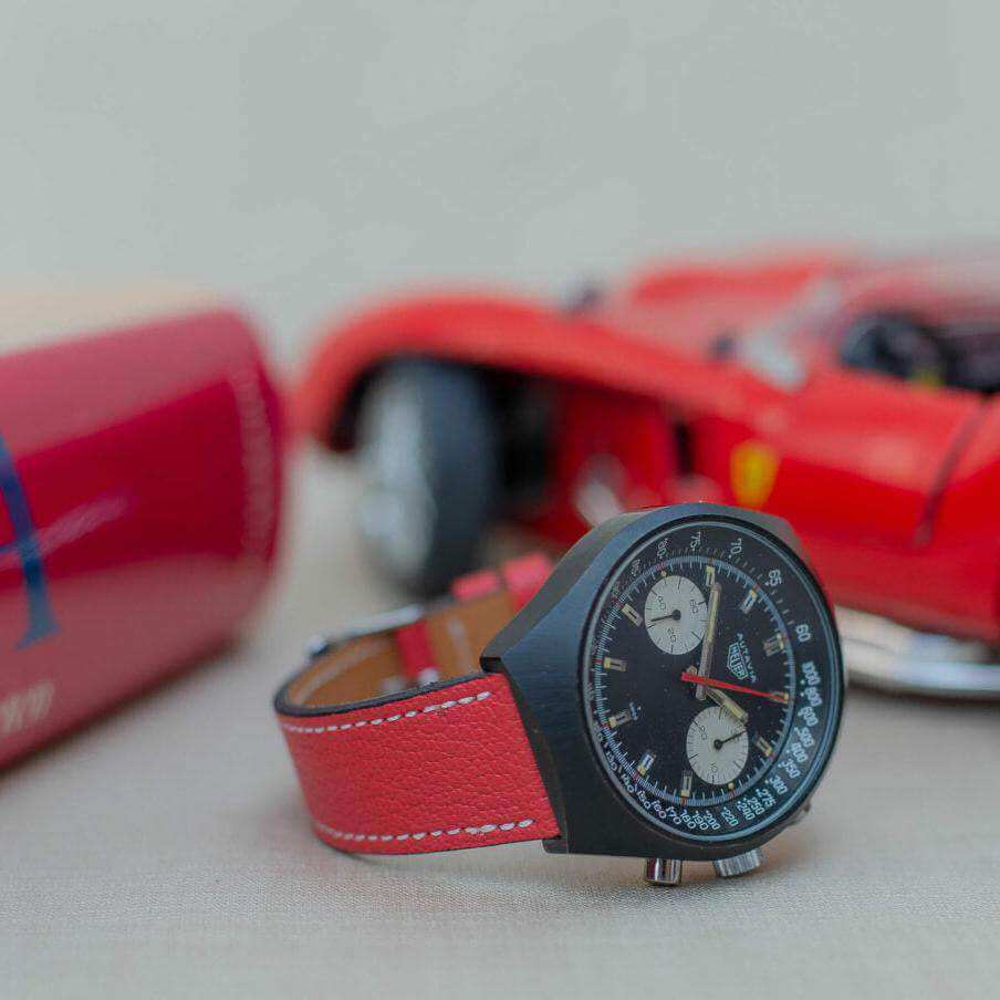 Seitlich fotografiertes rotes Ziegenlederarmband an einer Heuer Autavia, das sportlichen Stil und erstklassigen Komfort bietet