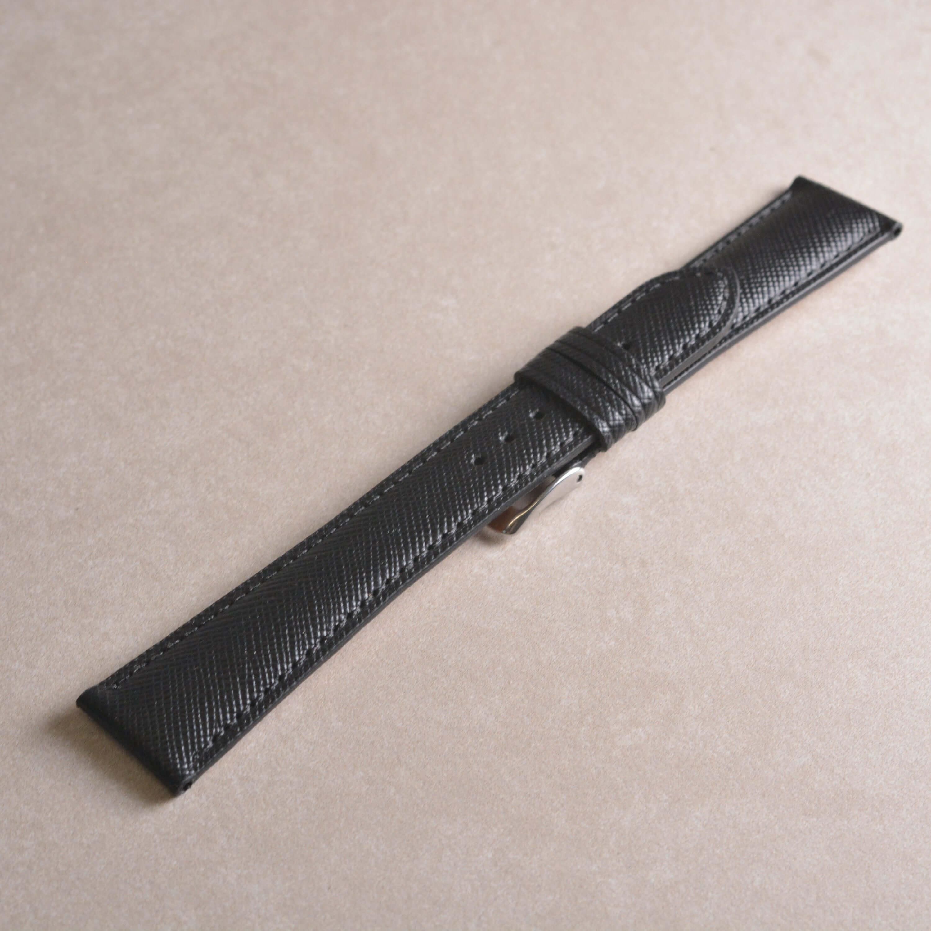 Saffiano – Uhrenarmband mit charakteristischer Saffiano Kreuzprägung auf hellem Hintergrund.