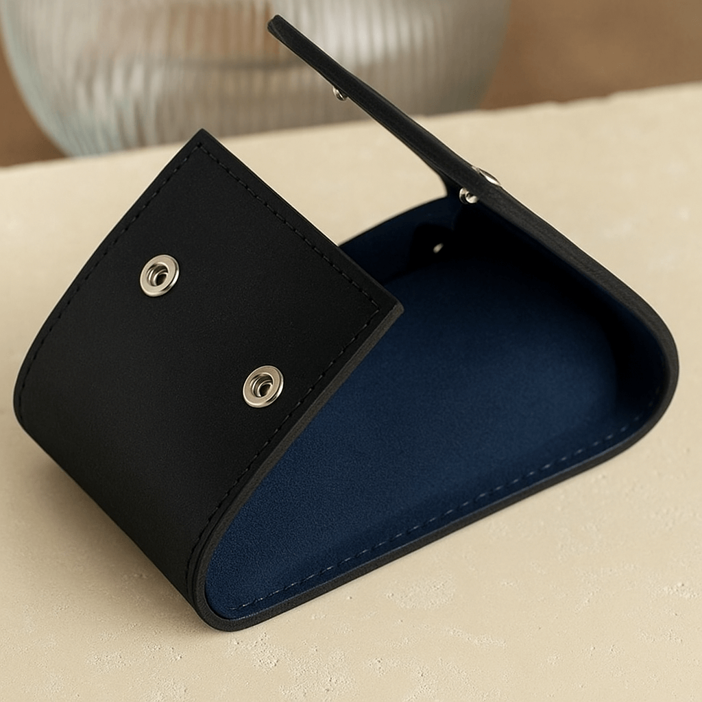 Moodbild eines geöffneten schwarzen Uhrenetuis mit blauem Alcantara-Innenfutter, stilvoll präsentiert auf einer Marmorplatte. Das luxuriöse Design und die hochwertigen Materialien bieten sicheren Schutz und eine elegante Aufbewahrung für Armbanduhren.
