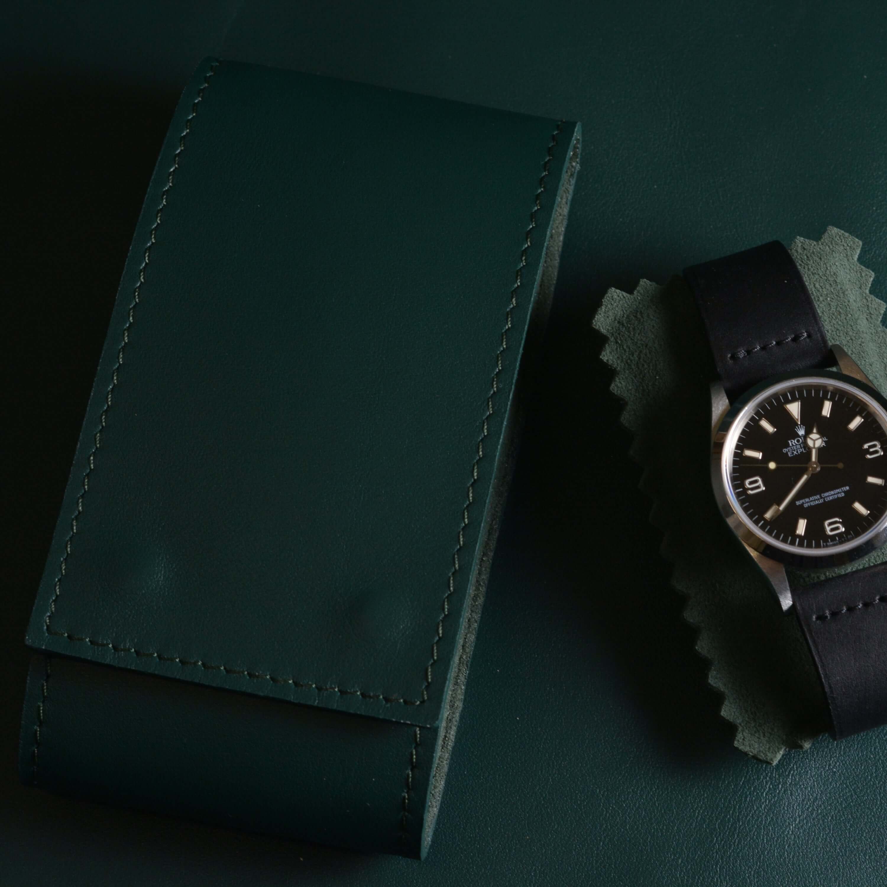 Edle Uhrenaufbewahrung in sattem Grün aus italienischem Leder, daneben eine Rolex Explorer Uhr– perfektes Reiseetui für Uhren mit Metall- oder Lederband, mit Alcantara ausgekleidet für maximalen Schutz.