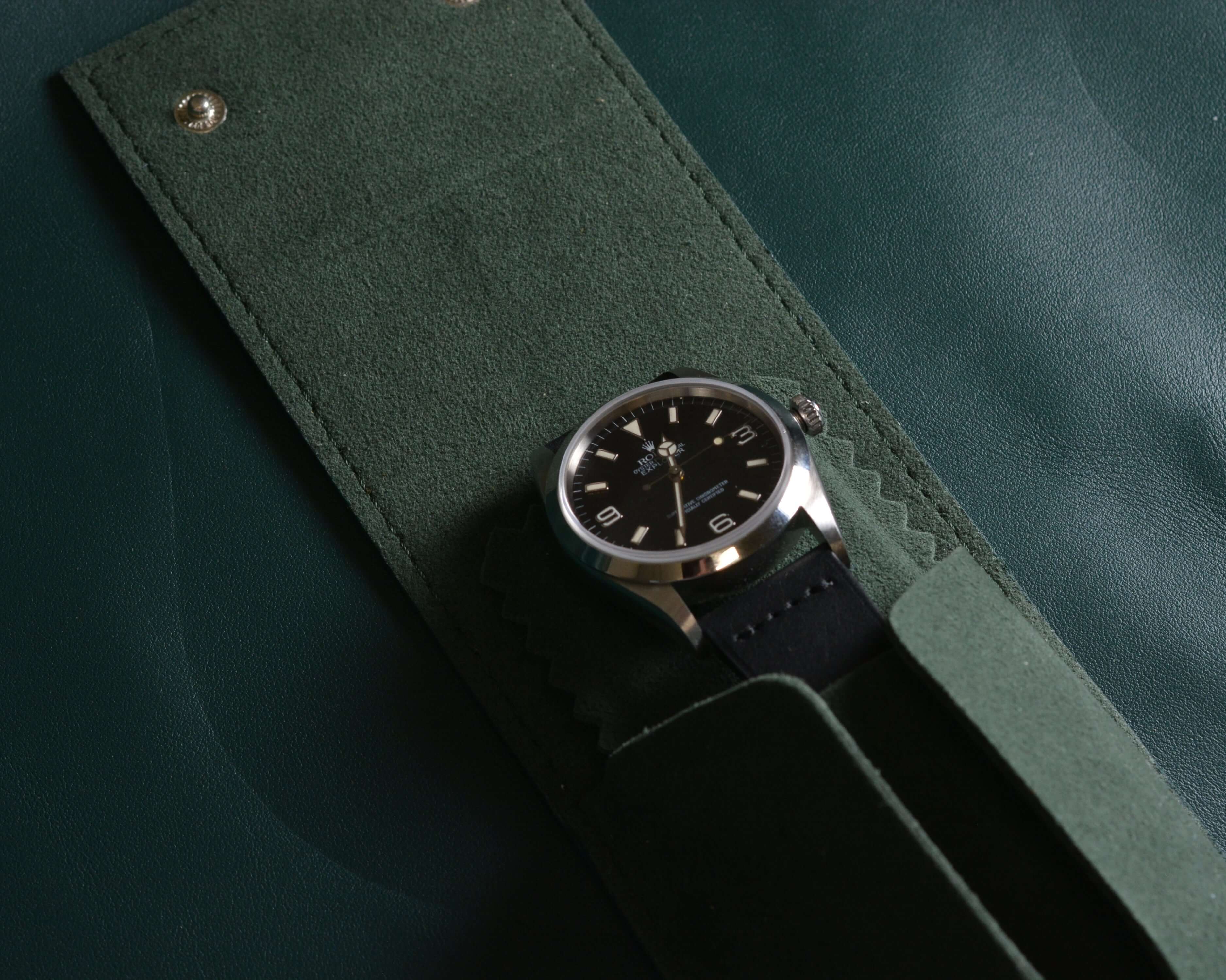 Detaillierte Nahaufnahme einer Rolex in einem offenen, grünen Uhrenetui aus feinem Leder mit Alcantara – luxuriöse Uhrenaufbewahrung mit sicherem Halt und elegantem Schutz.
