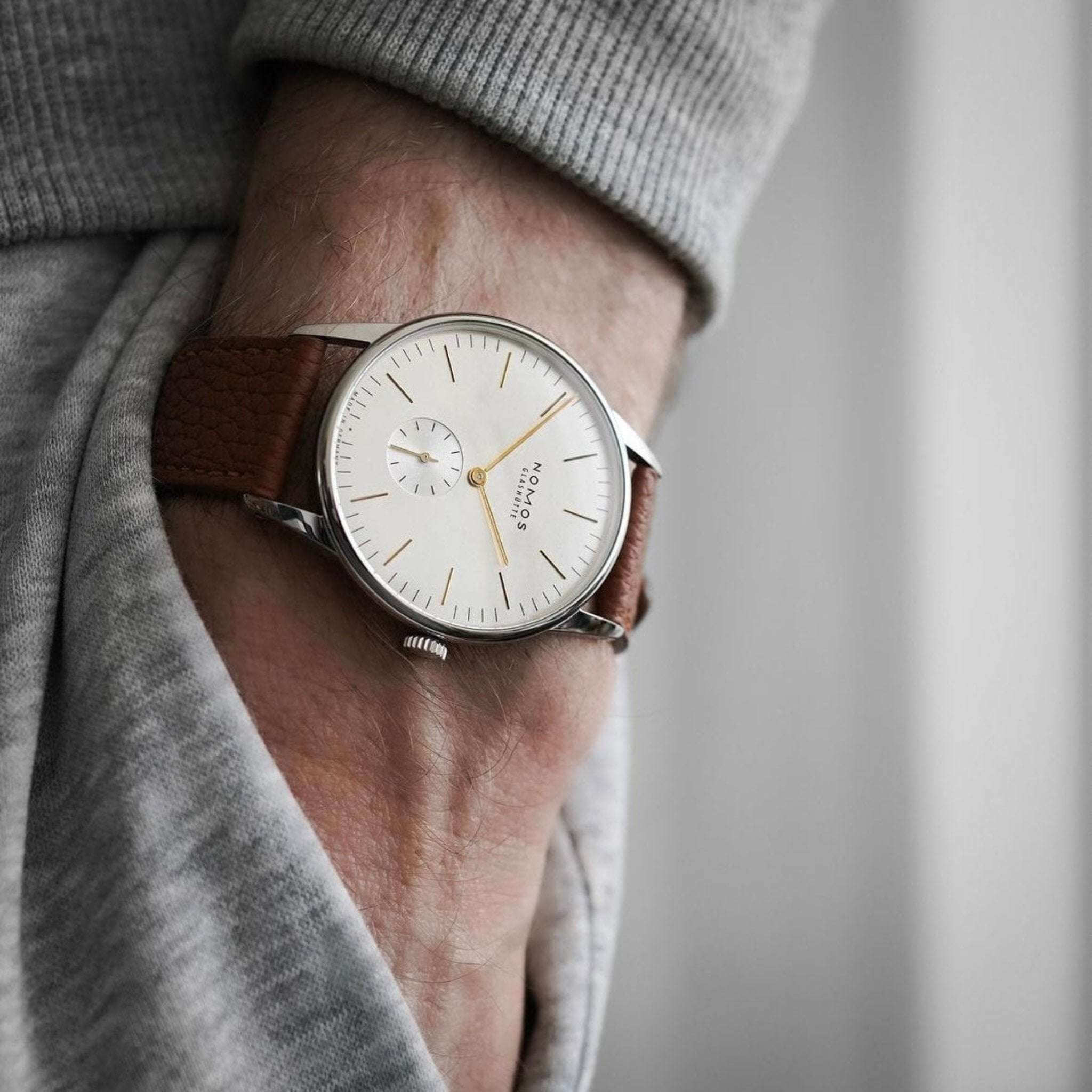 Whiskeyfarbenes Deauville Uhrenarmband aus Fjordleder am Handgelenk einer Nomos Orion Silber Uhr, Bild von awatchguyslife