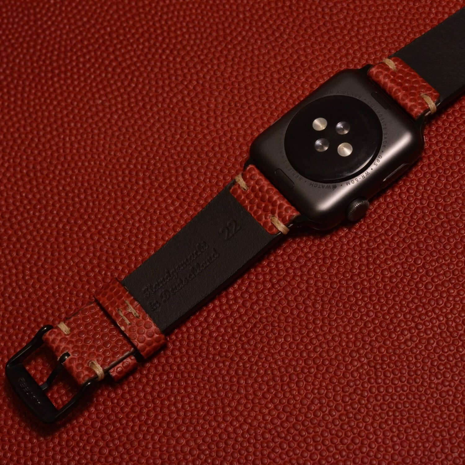 Apple Watch Band aus Wilson – Handgefertigt aus original Horween Footballleder in rot auf Lederuntergrund.