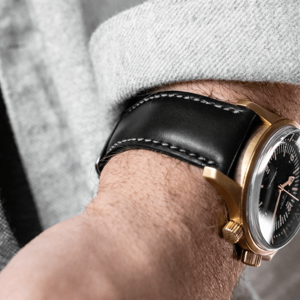 Yorkshire – Armband aus traditionellem englischem Bridle-Leder in Schwarz an einem Handgelenk, mit goldener Uhr.